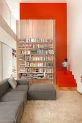 The stairs are partically hidden behind a slatted ash screen that supports steel bookshelves.