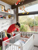 Kids Room, Shelves, Neutral Gender, Toddler Age, and Bedroom Room Type Baby Max’s bedroom (in his parents' Los Angeles A. Quincy Jones house) is outfitted with a Gulliver crib and a red PS cabinet, both from Ikea, as well as a Birds in Harmony mobile by Christel Sadde and Katsumi Komagata for the Museum of Modern Art Store. The custom “I brake for unicorns” neon sign is from Let There Be Neon, a shop in New York City.  Photo 10 of 34 in Babe in the Woods by Luanne  Sanders Bradley from A Midcentury Home Keeps the History Alive