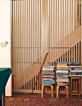 Books from Aulenti’s extensive library overflow onto stools—designed by Alvar Aalto and produced by Artek—in her bedroom. The door handle, Otto A, is her own design for Fusital, from 1978.  Photo 3 of 6 in The Elegant Milan Home of Designer Gae Aulenti
