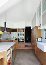 Brisbane-based studio Owen and Vokes and Peters designed a modern kitchen addition for a traditional Queensland-style timber house. Glossy Vogue Ghiaccio kitchen tiles set off custom cabinetry built by Cooroy Joinery & Woodworks using American oak veneer and Centor doors. The dishwasher is by AEG.