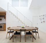 “We refaced some of the kitchen cabinets and altered the staircase a little bit,” Miller says. The new staircase features a design that accommodates storage for a microwave and pantry items. A warm wood dining table by Matthew Hilton and Profile chairs from Design Within Reach stand out against the white walls and pale flooring.