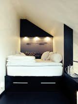 In the tiny sleeping loft is a platform bed with two drawers beneath it. In place of wallpaper, Schönning enlarged a photograph he snapped in Rio de Janeiro. The inset spotlights and a small shelf at the end of the bed offer light and additional storage. Photo by Per Magnus Persson.  Photo 2 of 6 in How To Use Color in Small Spaces by Dora Vanette