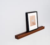 The Rail Box from On Our Table is a simple wall-mounted piece crafted from solid black walnut. The simple box makes it easy to display one frame or several, and art can be changed out easily. The Rail can also be used to hold postcards and unframed prints—it can even be used in a kitchen to display a recipe for easy reference.
