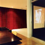 The kitchen transitions into the living room, which transforms easily into a home theater when the heavy red drapes are pulled tightly shut. The home theater system features a projector by Sharp.  Search “theater” from Making Sense of the City