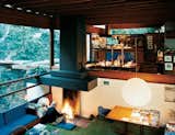 Los Angeles architect Ray Kappe sits at the central hearth on the north end of the comfortable sunken living area. From this perspective, you can see how the interior spaces flow into one another, passing one half-level up into the breakfast nook and kitchen and out from there onto the overgrown hillside. The various built-in furnishings have all been there since the house's construction.