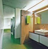 The bathroom is a long, linear space with a letterbox window to provide natural light. There are two toilets, a pair of sinks, and two showers.