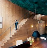 In Amsterdam, architect Pieter Weijnen designed a hovering, blue-green ceiling composed of copper plates for his dining room. The curved shape of the mass, in concert with the knotted wood of the stairs and walls in the space, creates a sense of being enveloped in warm-toned, handmade textures and materials.