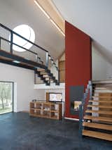 Staircase, Metal Railing, and Wood Tread Circular “sun disks” cut into the slanted roof create light shafts that move throughout the day, casting angular shadows as they pass over the steel staircases and catwalk.  Photo 16 of 18 in 18 Luminous Homes With Interesting Skylights from A Striking Bohemian Geothermal Home
