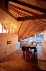 Angled openings in the roofline function as both windows and vents, allowing views and cross-breezes. A dining table completes the nearly all-wood room.