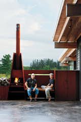 Outdoor, Large Patio, Porch, Deck, and Concrete Patio, Porch, Deck Sherbanuk (left) and Campbell sit by the outdoor fireplace, which adjoins the screened-in porch.  Photo 12 of 18 in couleur by Gemma Savage from Scrap House