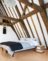 "Instead of the disappointment we anticipated, there was yet another great space, with an incredible beamed ceiling," says Hindman of seeing the top-floor bedroom for the first time. The wooden frame was left in its natural state. Rody Grauman's 85 Lamps chandelier, a classic from Droog Design, places the 17th-century room squarely in the present.