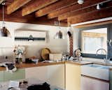 The architects kept the low-beamed ceiling, retaining the house's English countryside charm. The kitchen features custom cabinetry designed by artist Neil Jolliffe. The couple purchased their Banksy prints from the artist's London gallery, Tom Tom.