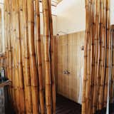 The six-by-six-foot shower boasts a hardwood-slatted deck, which allows water to seep into a concrete pan that empties into the main drainage system. The cage of bamboo poles provides the requisite privacy to the bather.