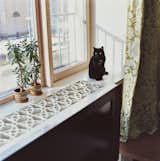 Moby the cat sits on the windowsill, which the architect constructed by cutting a geometric pattern into a thick sheet of MDF, a fiberboard product that’s inexpensive, easy to machine, and unrecognizable when coated in white lacquer paint.