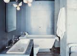 Winged light bulbs, part of an Ingo Maurer fixture, bring levity to this bathroom. The space features a zinc wall by Houston metalworker George Sacaris, who also did the bathroom and kitchen cabinets.