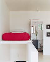 The bed is perched above the staircase leading from the second-story living area to the third-story sleeping area.