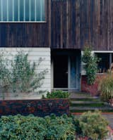 The home’s entry as it is today is a planar collage of right angles and various materials. White reused as much of the original home as possible, such as the siding seen here, and added a second story.