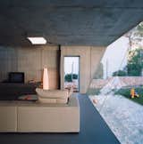Living Room, Sofa, Ceiling Lighting, and Concrete Floor On the living room ceiling a Sivra fixture by iGuzzini modulates its output based on the amount of available daylight. The sofa is Wall by Piero Lissoni for Living Divani.  Photo 5 of 10 in Suburban House of the Future by Cloud9