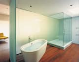 A translucent wall silhouettes a Duravit bathtub by Philippe Starck in the master bathroom.