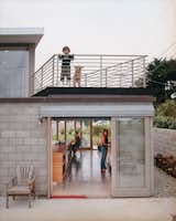 Exterior, Concrete Siding Material, and House Building Type The couple’s son Dylan and dog Petra enjoy the deck while Mary Kate and Thomas work in the kitchen below. Sliding doors open to the outdoors on both sides.  Photos from The Full Montara
