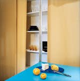 Hughston keeps all his tableware behind the curtain, on the shelves nearest the kitchen. The ample shelf space, covering the entire wall (except that taken up by the Murphy bed), makes it easy for Hughston to avoid mess. The contrast of gold and turquoise is warm and lively.