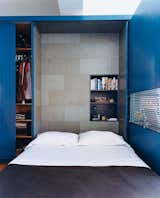 The interior of the Murphy bed compartment is lined with a stained cork panel and contains a smaller shelving unit for bedside reading, alarm clock, and reading lamp.