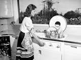 Mrs. Fritz Burns in her dream kitchen, using her built-in hydraulic dishwasher, in a Los Angeles house designed and built in 1946 in by her contractor husband, Bob Landry.