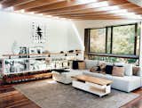 Living Room, Rug Floor, Sectional, Dark Hardwood Floor, Shelves, and Coffee Tables Exposed timber rafters support the roof, which is peeled back at the rear of the site to draw in warmth from the northern sun.  Search “striking blackened timber house built site fire” from A Measured Approach