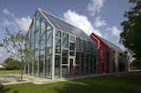 The house, built by de Rijke, Marsh and Morgan (dRMM), is a 3-in-1 building that slides along railroad tracks recessed into the concrete foundation. A greenhouse-like glass interior structure is exposed through the sliding movement of the red rubber and larch sheaths that form the exterior walls.  Photo 8 of 8 in Rubber-Made: 8 Great Interiors and Products by Kelsey Keith from Sliding House