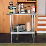 The kitchen island—–an equipment stand purchased from online restaurant supplier Serv-U—is essential in providing much-needed counter space. The bottom shelf creates additional storage and the outlets mounted underneath allow it to become a coffee and toast center. Because it’s stainless steel, the family can put a hot pan right on the surface without worrying about trivets—which are hard to keep handy in such a small place.  Photo 8 of 9 in Built-In Style
