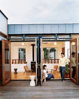 Jinhee Park and John Hong, in a doorway that opens to the building’s shared roof deck. Behind them is the upstairs lounge of their neighbors, adorned with Eames chairs, Kartell stools, and a woodstove from Rais Wittus.