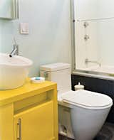 Bath Room, Porcelain Tile Floor, Vessel Sink, and One Piece Toilet To save money and time, the architects used similar designs for the bathrooms 

in both their and Andy’s apartment: Philippe Starck toilets, fixtures from New York’s AF Supply, and custom cabinets painted with watertight auto-body paint.  Photo 7 of 11 in C o l o r S p l a s h by Matthew Terry from Beantown Dream