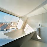The cavity for the bathtub is part of the same continuous form-world as House Ray 1’s sloping roofscape. The white tub is made from Corian; the faucet is by Dornbracht.