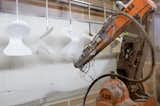 A robotic arm paints the hanging chairs for optimum coverage.