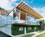 The house has what some architects would call an upside-down plan, with living spaces upstairs and bedrooms below. The upper story is strikingly transparent; the lower is camouflaged by thick, foliage-covered walls, which keep the sleeping areas cool.