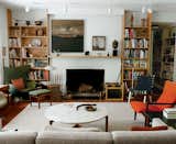 In legendary designer Jens Risom’s home, the painted white brick fireplace is flanked by wood bookshelves that join to form a mantle.