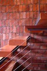 The steps of the stairs were made from pieces of wood leftover from salvaged timbers used elsewhere in the house. Moore added a windor in the roof to bring light into the core of the house and didn’t want to diminish its effect with risers so he cantilevered the steps from the central brick wall. “The residents also wanted the house to feel like a tree fort,” Moore says. “These steps look a little risky to climb up but they’re actually super solid.”

Photo courtesy of Mike Moore/Tres Birds Workshop