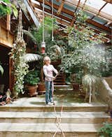 Sue waters the indoor foliage with an industrial hose hung from the ceiling.