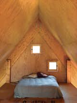 Bedroom and Bed In the third-floor bedroom, peekaboo windows offer a glimpse of the surrounding fields.  Photo 5 of 11 in Modern Wooden A-Frame Retreat in France