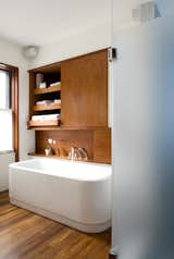 The leftmost cabinet above the Duravit bathtub (equipped with KWC fixtures) occupies the space where a doorway once lead into the living room, creating unnecessary traffic from the home’s public spaces through to the master bedroom. The new bathroom features a minimal palette of white and teak. "It’s able to hold up on boat decks so is good for a bathroom," Klug says. It also makes the heated floor that much nicer to walk on in the morning.