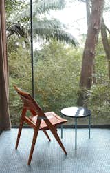 Her folding side chair, against the floor-to-ceiling window wall of the Glass House. Photo courtesy Espasso.