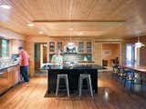 In the kitchen, Danish PH 5 lamps illuminate the island and table. The lined wood planks on both the ceiling and floor draw the eye naturally through the space to the study beyond, where Keith’s father’s original Jens Risom desk resides.