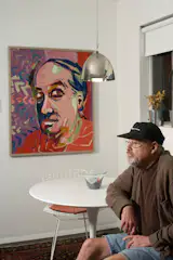 Ronald Popp, with a self-portrait in the dining zone off the kitchen. The Harry Bertoia chairs are from his existing collection; their orange pads served as the design springboard for the kitchen cabinetry. Popp acquired the Eero Saarinen table for the space.  Photo 6 of 6 in Renovation: 800 Square Feet