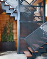 The steel stairwell that connects the garden-level patio with the new living space performs double duty as an anchor attached to the foundation.