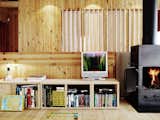 Exposed pine boards dominate the interior, giving a subtle, warm backdrop to the splashes of color that his stove and collection of books provide.