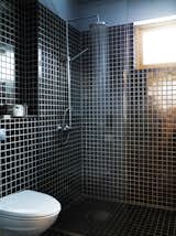 Simple black tiles and a basic, exposed showerhead kept costs down, allowing other parts of the house to function as the showpieces.