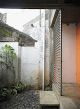 An orange door and metal grille make for a warm, if industrial, contrast to the stones and plants on the patio. They also weather well, something critical in a place where the climate leads to a palpable sense of decay.