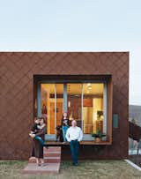 The house is clad with scales made of Cor-Ten steel that have weathered and rusted over time and create framed views into rooms like the kitchen.