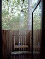 An aluminum-and-glass door, chosen for its ability to handle exposure to water, leads from the bathroom to the outdoor shower.  Photo 6 of 7 in Outdoor Showers We Love by Zach Edelson from Texas Bunkhouse