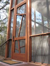 The nine-by-three-foot mahogany entrance door is meant to evoke the surrounding trees. The iron handrails lining the base of the porch are a subtle architectural detail, as well as a support system to prevent the cabin from ever twisting or shifting “like so many old Texas outbuildings,” says Panton.